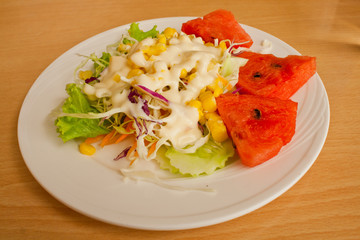 Salads, vegetables and fruit on a white plate