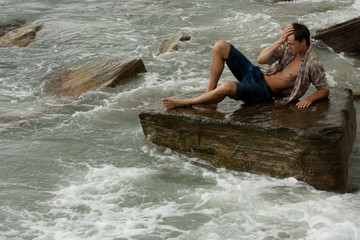 brawny lad on stone at sea