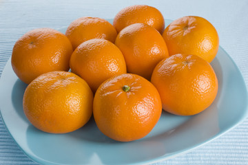 Ripe fresh tangerine on blue plate