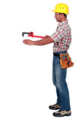 Tradesman using a pipe wrench to help drag and place an object
