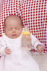 sleeping newborn baby girl after drinking milk from a bottle.