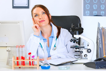 Female medical doctor sitting in cabinet and dreaming