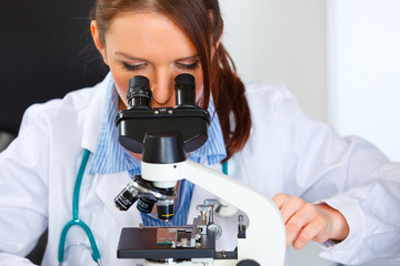 Closeup on doctor woman working with microscope in laboratory