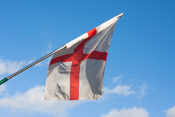 English flag hanging from mast against blue sky