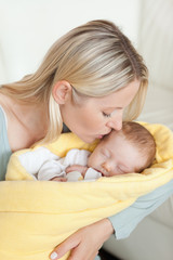 Fototapeta na wymiar Affectionate mother kissing her baby's forehead