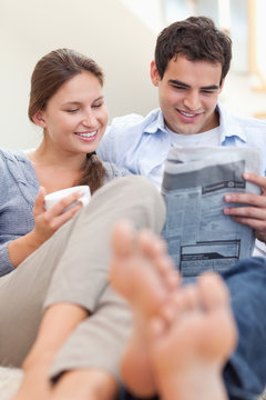 Couple reading a newspaper while lying on a couch