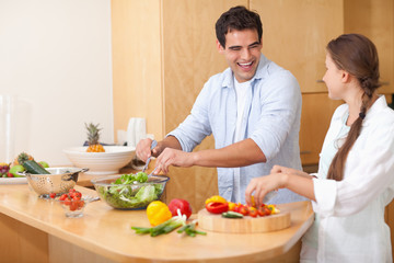 Obraz na płótnie Canvas Smiling couple preparing a salad