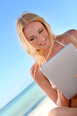 Blond woman using electronic tablet at the beach
