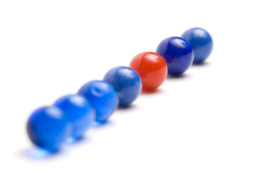 One red vintage marble standing out from blue