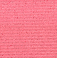 Fototapeta premium A detailed macro shot of a rough, granular pink paper surface featuring a prominent horizontal ribbed pattern, ideal for use as a textured background.