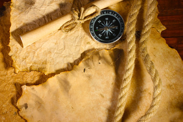 old paper, compass and rope on a wooden table