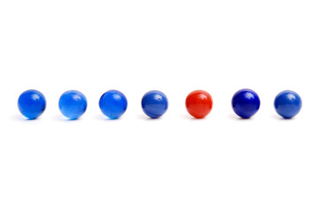 Red vintage marble standing out from blue marbles