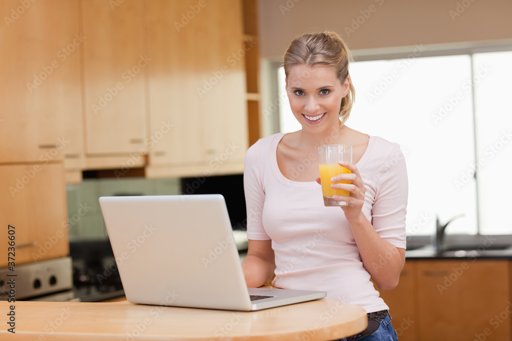 Poster Woman using a notebook while drinking juice