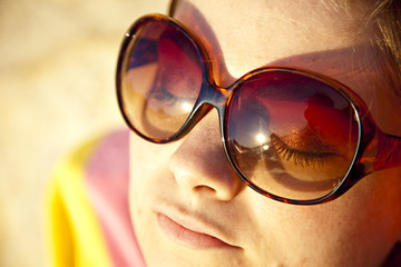 femme a lunettes de soleil bronze sur la plage