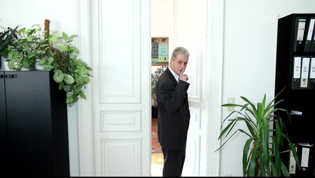 Ein Mann in einem B&uuml;ro fordert zum Schweigen auf