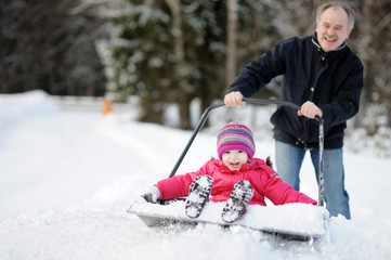 Winter fun: little girl having a ride on a snow shovel