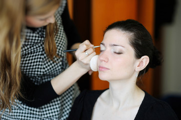 Young beautiful woman applying wedding make-up by make-up artist