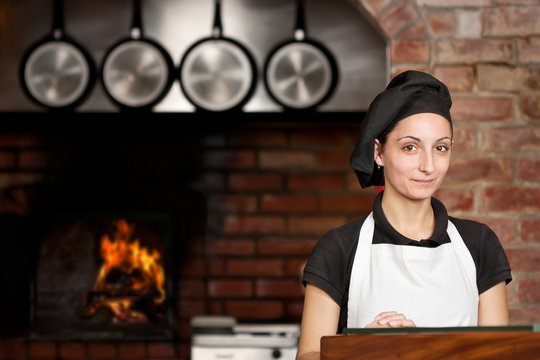 Woman Chef stand in the kitchen near wood oven