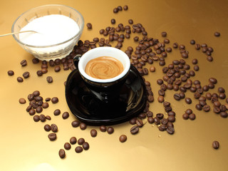 caffe espresso con zucchero e chicchi di caffe su sfondo oro