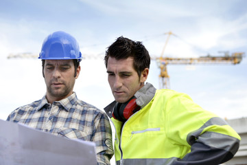 two supervisors on a construction site looking at a blueprint