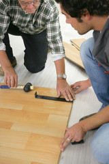 Father and son installing wooden flooring