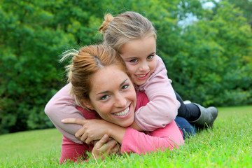 Little girl and mother laying on grass in park