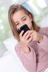 Portrait of little girl writing short message on mobile phone