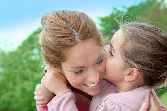 Portrait of little girl giving kiss to her mom