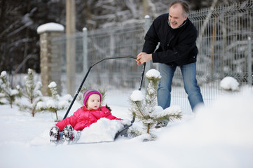 Fototapeta na wymiar Zimowe zabawy: dziewczynka o jazdę na śniegu łopatą