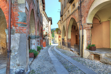 Old narrow street among ancient houses in Avigliana, Italy.