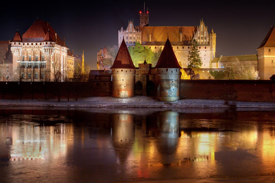 Fototapeta Malbork castle in Poland at night with reflection in Nogat river