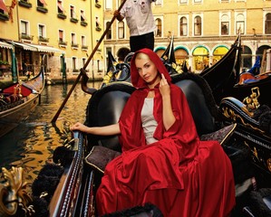Fototapeta na wymiar Beautifiul woman in red cloak riding on gandola