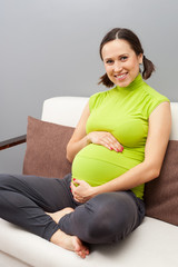 Obraz premium smiley pregnant woman sitting on sofa