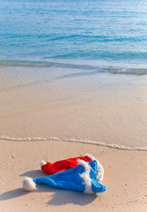 Two New Year's caps of Santa Claus on beach