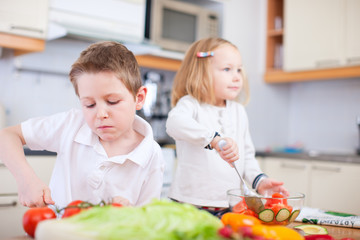 Two little kids making salad