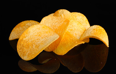 Delicious potato chips on black background