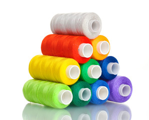 Pyramid of many-coloured bobbins of thread isolated on white