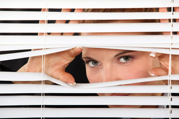 Woman peering through blinds