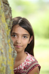 A little Latina hiding behind a tree.