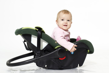 The little girl sits in an automobile cradle