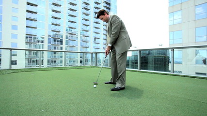 Young Businessman Practicing Golf on Office Rooftop - Powered by Adobe