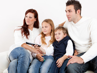 Cheeful young family watching TV at home