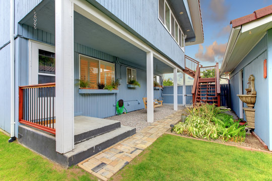 Court yard fenced with blue house and garage.