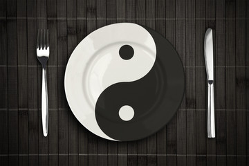 yin yan plate over bamboo placemat setting with fork and knife