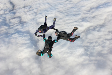 Fototapeta na wymiar Trzy Skydivers w spadania nad bankiem chmur