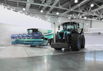 Big tractor and harvester are in room at exhibition - obrazy, fototapety, plakaty