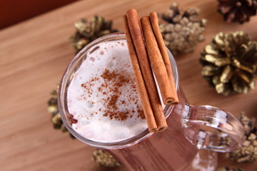 Cup of hot chocolate with cinnamon sticks and cones