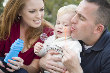 Young Parents Blowing Bubbles with their Child Boy in Park