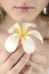 Obraz na płótnie Canvas Close up young beautiful woman with a frangipani flower