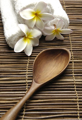 Obraz na płótnie Canvas Roller towel with frangipani and spoon on mat